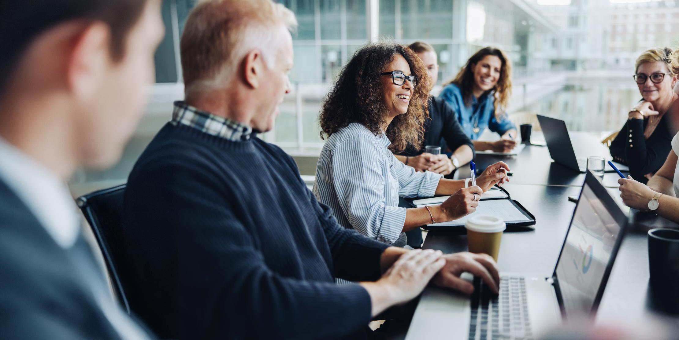 Mehrere Personen sitzen im gemeinsamen Termin mit ihren Laptops am Tisch