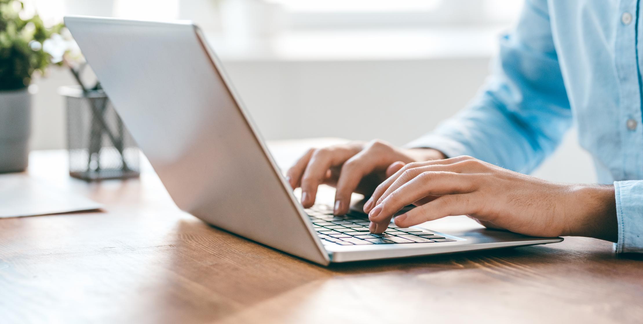 Person tippt Inhalte auf einen Laptop