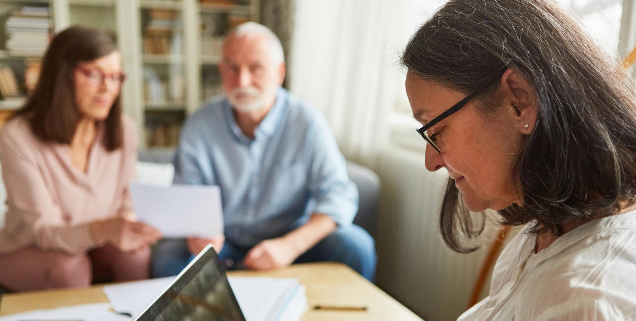 Drei Personen beantragen gemeinsam Leistungen mit einem Laptop