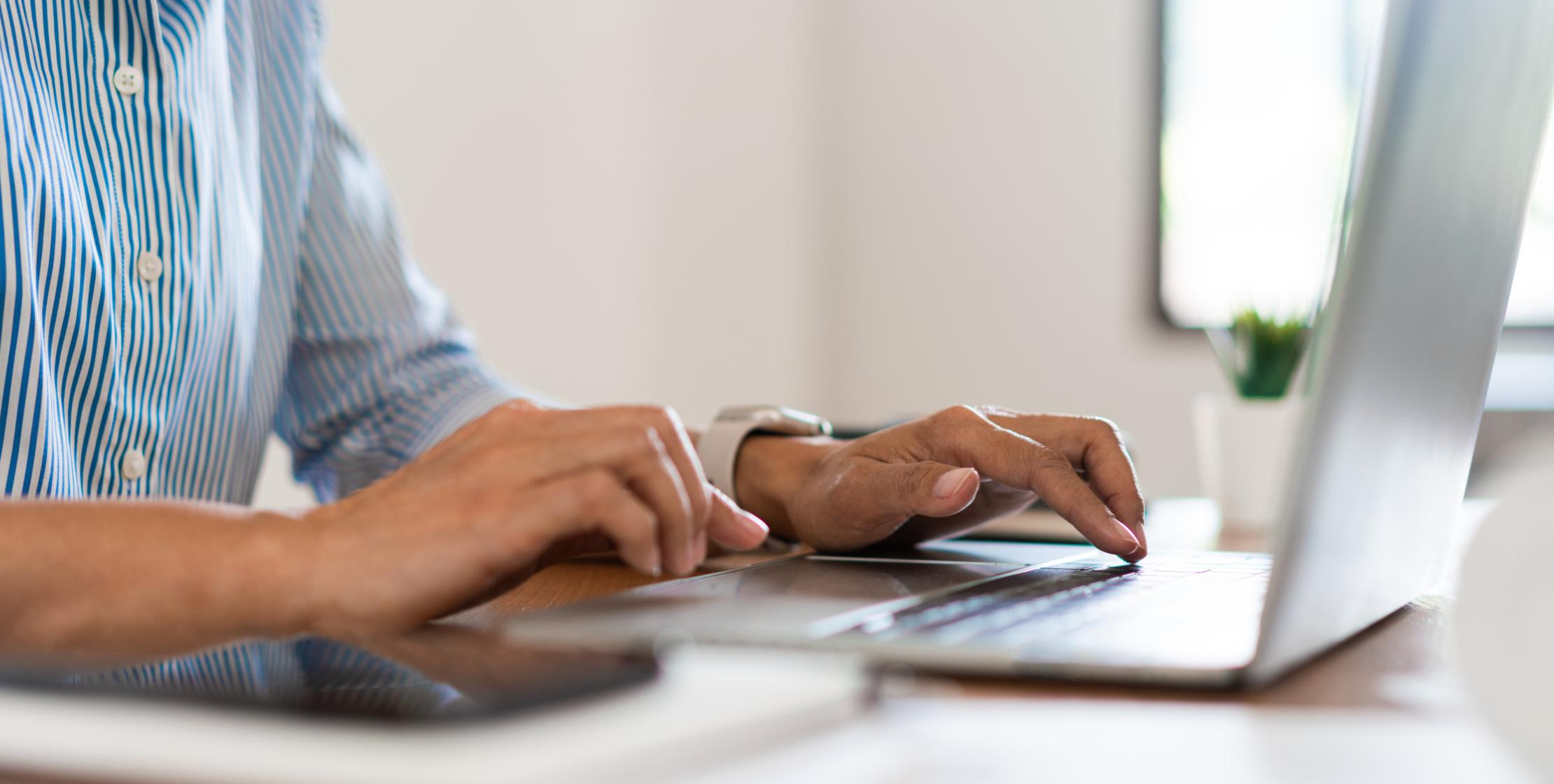 Foto von Person die am Laptop arbeitet und etwas eintippt